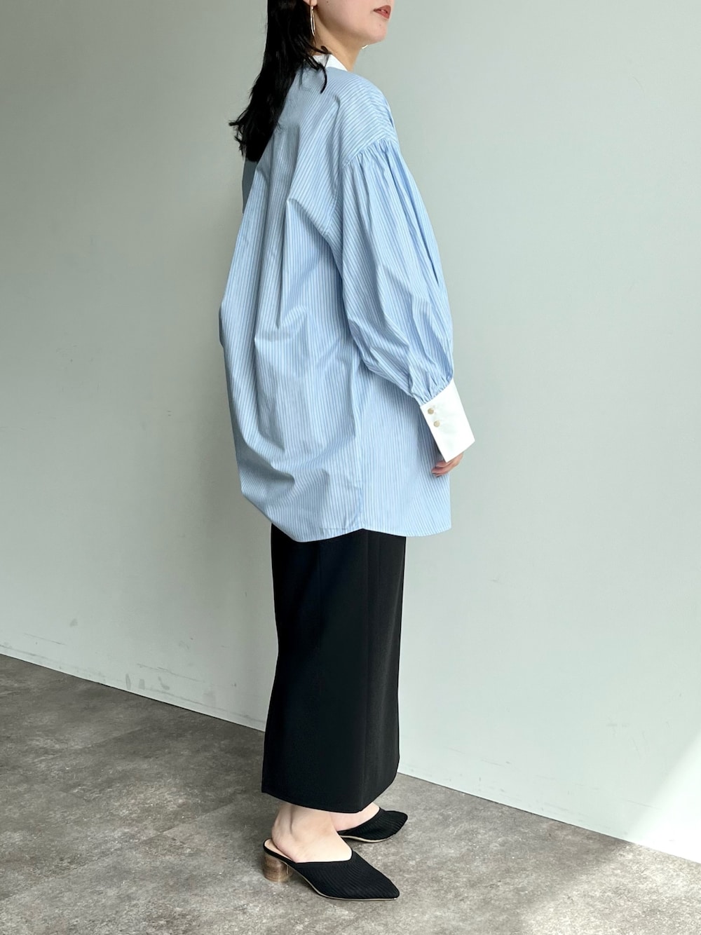 ブラック系のスカート、ブルー系のシャツ/ブラウス、ブラック系のパンプスを着用したレディースの春コーディネートの2枚目の写真