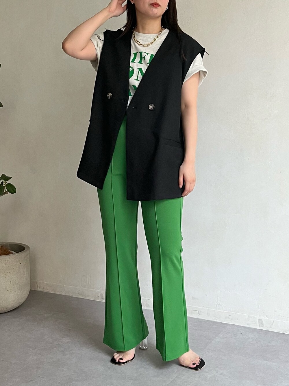 ブラック系のベスト、グリーン系のその他パンツ、ホワイト系のサンダルを着用したレディースの春コーディネートの2枚目の写真