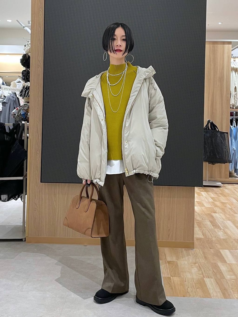 ベージュ系のダウンジャケット/コート、ブラウン系のその他パンツ、ベージュ系のショルダーバッグを着用したレディースの冬コーディネートの1枚目の写真