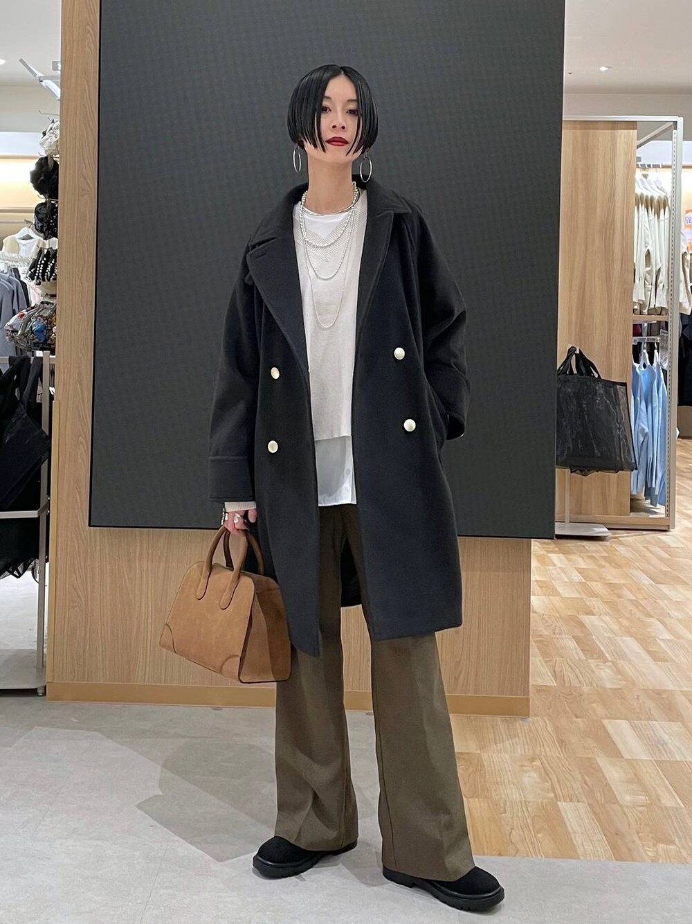 ブラック系のチェスターコート、ホワイト系のニット/セーター、ブラウン系のその他パンツを着用したレディースの冬コーディネートの1枚目の写真