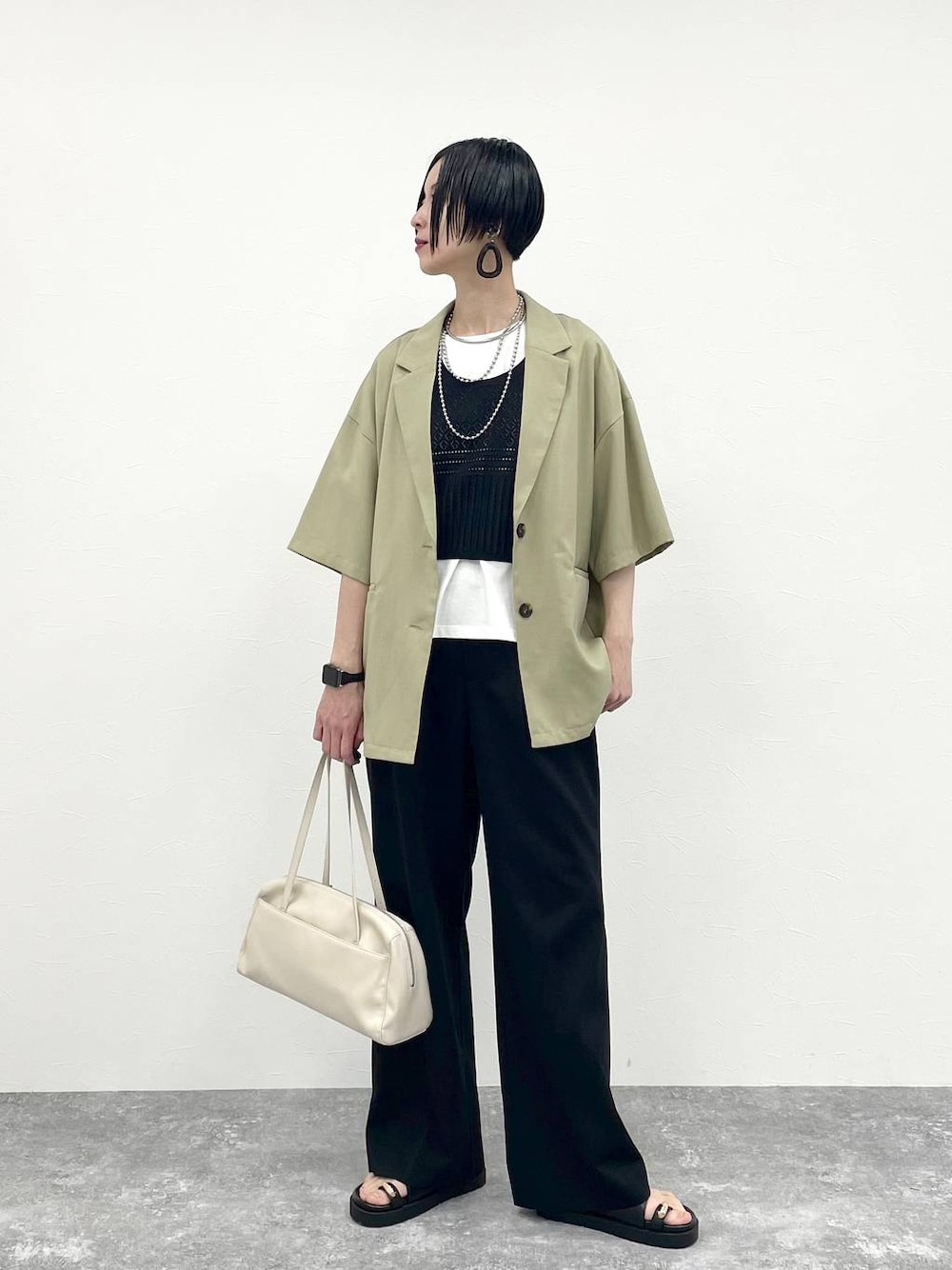 ブラック系のその他パンツ、ホワイト系のTシャツ/カットソー、ベージュ系のショルダーバッグを着用したレディースの春コーディネートの1枚目の写真