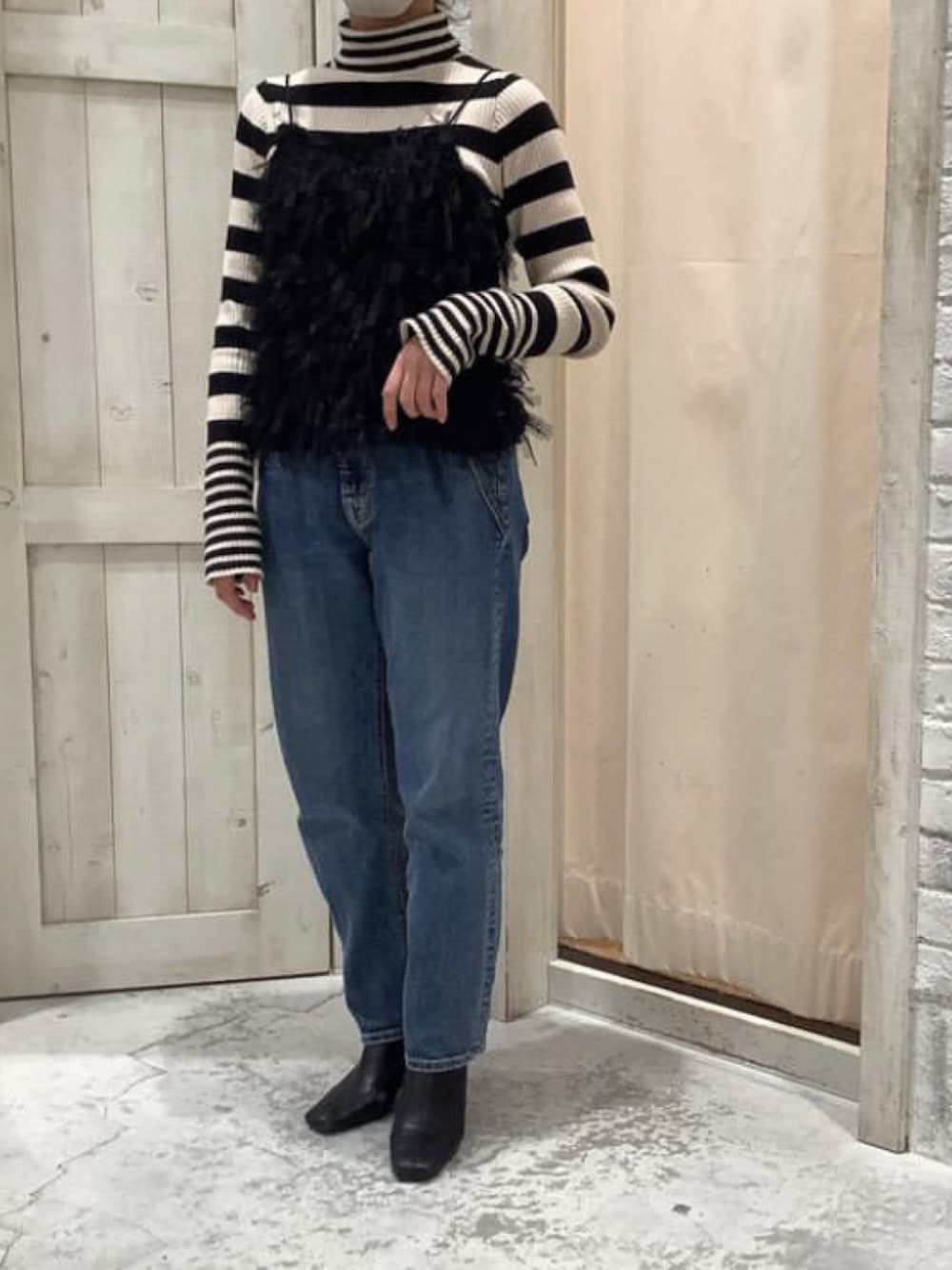 ブルー系のデニムパンツ、ブラック系のキャミソール、ホワイト系のニット/セーターを着用したレディースの冬コーディネートの1枚目の写真