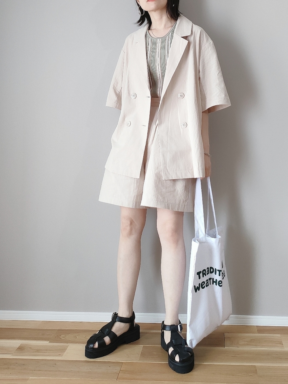 ベージュ系のテーラードジャケット、ベージュ系のその他パンツ、ホワイト系のトートバッグを着用したレディースの春コーディネートの1枚目の写真