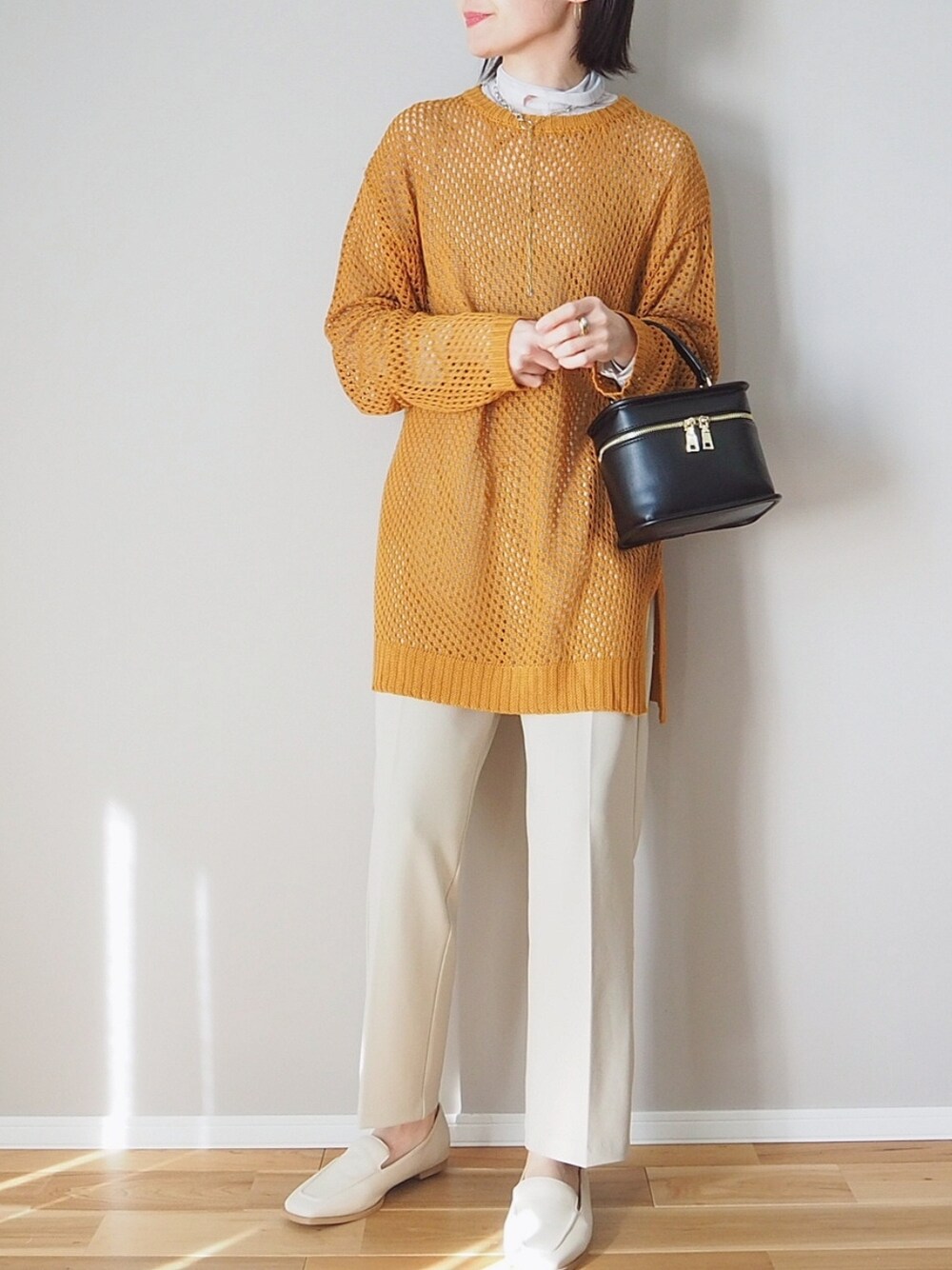 オレンジ系のニット/セーター、ベージュ系のスラックス、ブラック系のショルダーバッグを着用したレディースの冬コーディネートの3枚目の写真