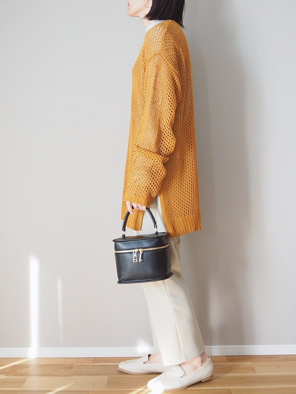 オレンジ系のニット/セーター、ベージュ系のスラックス、ブラック系のショルダーバッグを着用したレディースの冬コーディネートの4枚目の写真