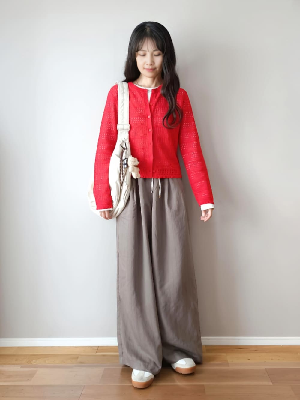 グレー系のその他パンツ、レッド系のカーディガン/ボレロ、ホワイト系のショルダーバッグを着用したレディースの春コーディネートの1枚目の写真
