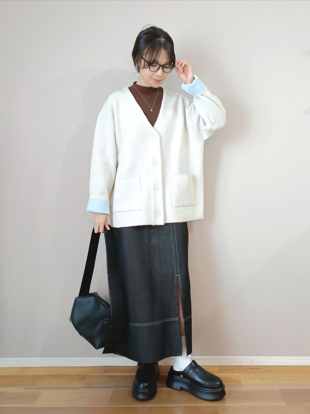 ホワイト系のカーディガン/ボレロ、ブラック系のスカート、ブラック系のスリッポンを着用したレディースの冬コーディネートの1枚目の写真