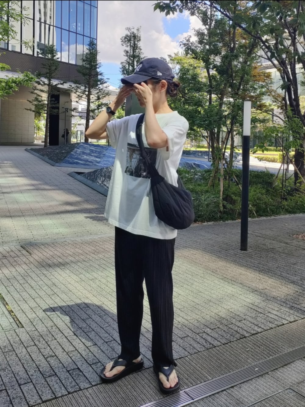 ホワイト系のTシャツ/カットソー、ブラック系のサンダル、ブラック系のショルダーバッグを着用したレディースの秋コーディネートの1枚目の写真