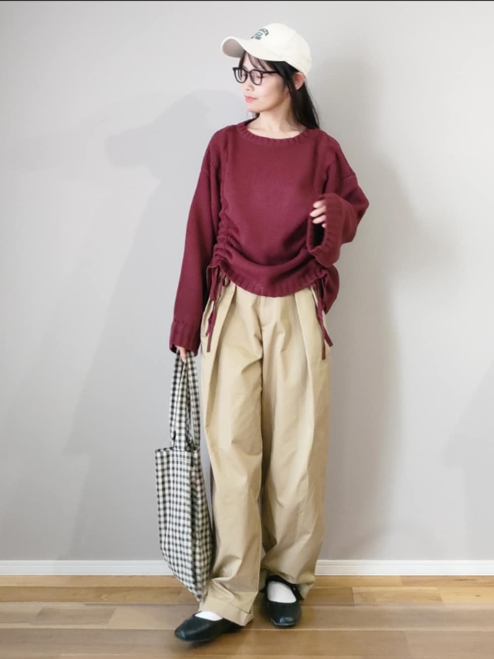 レッド系のニット/セーター、ベージュ系のチノパンツ、ベージュ系のトートバッグを着用したレディースの秋コーディネートの1枚目の写真