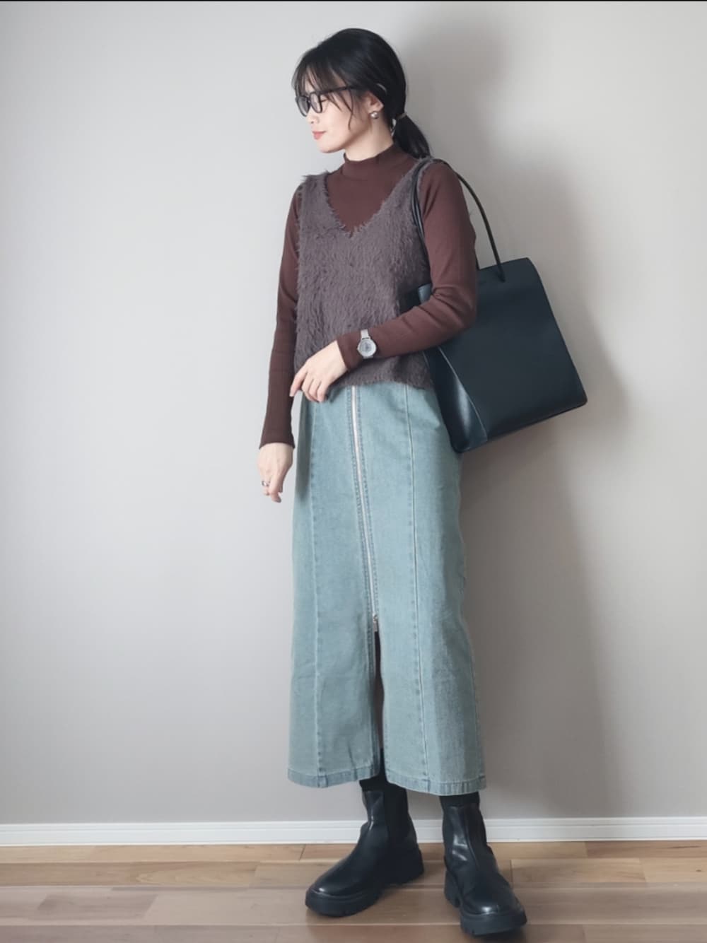 ブラック系のスカート、グレー系のベスト、ブラック系のブーツを着用したレディースの冬コーディネートの1枚目の写真