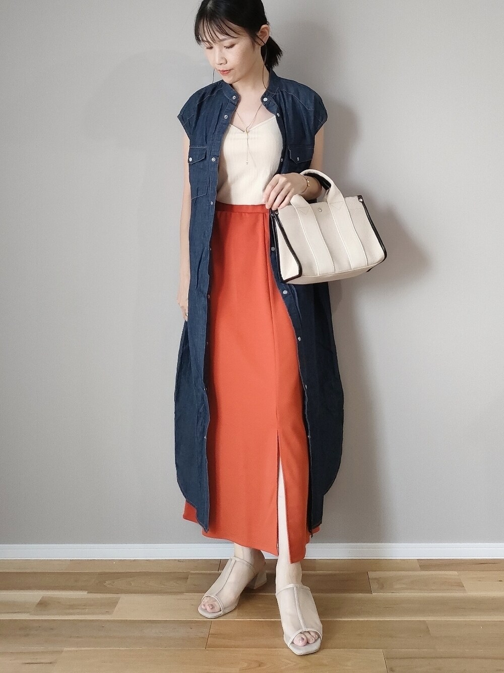 オレンジ系のスカート、ホワイト系のキャミソール、ブルー系のワンピースを着用したレディースの夏コーディネートの1枚目の写真
