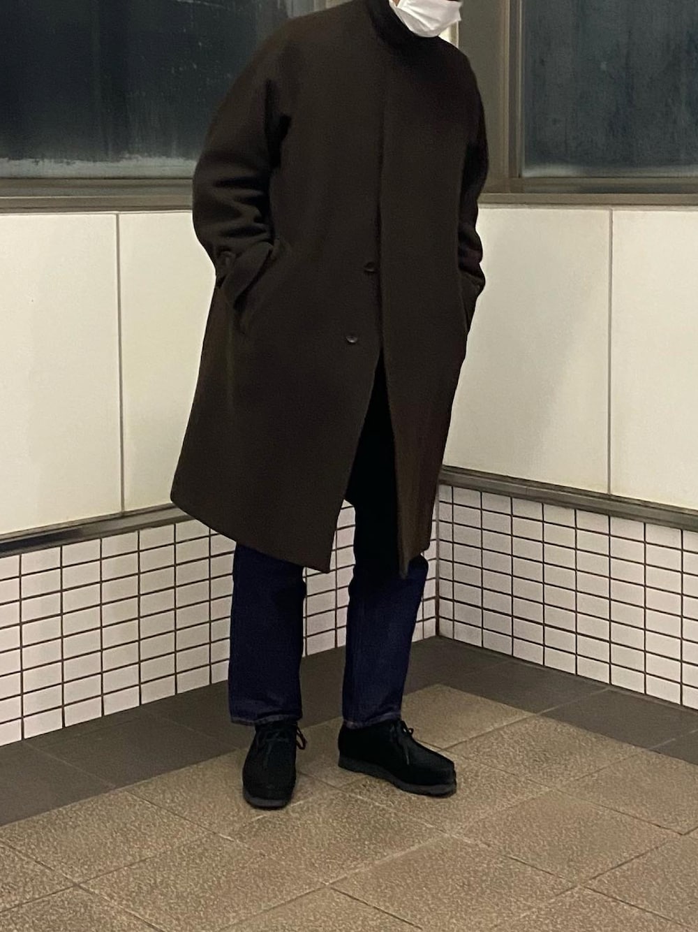 ブラウン系のステンカラーコート、ブルー系のデニムパンツ、ブラック系のブーツを着用したメンズの冬コーディネートの1枚目の写真