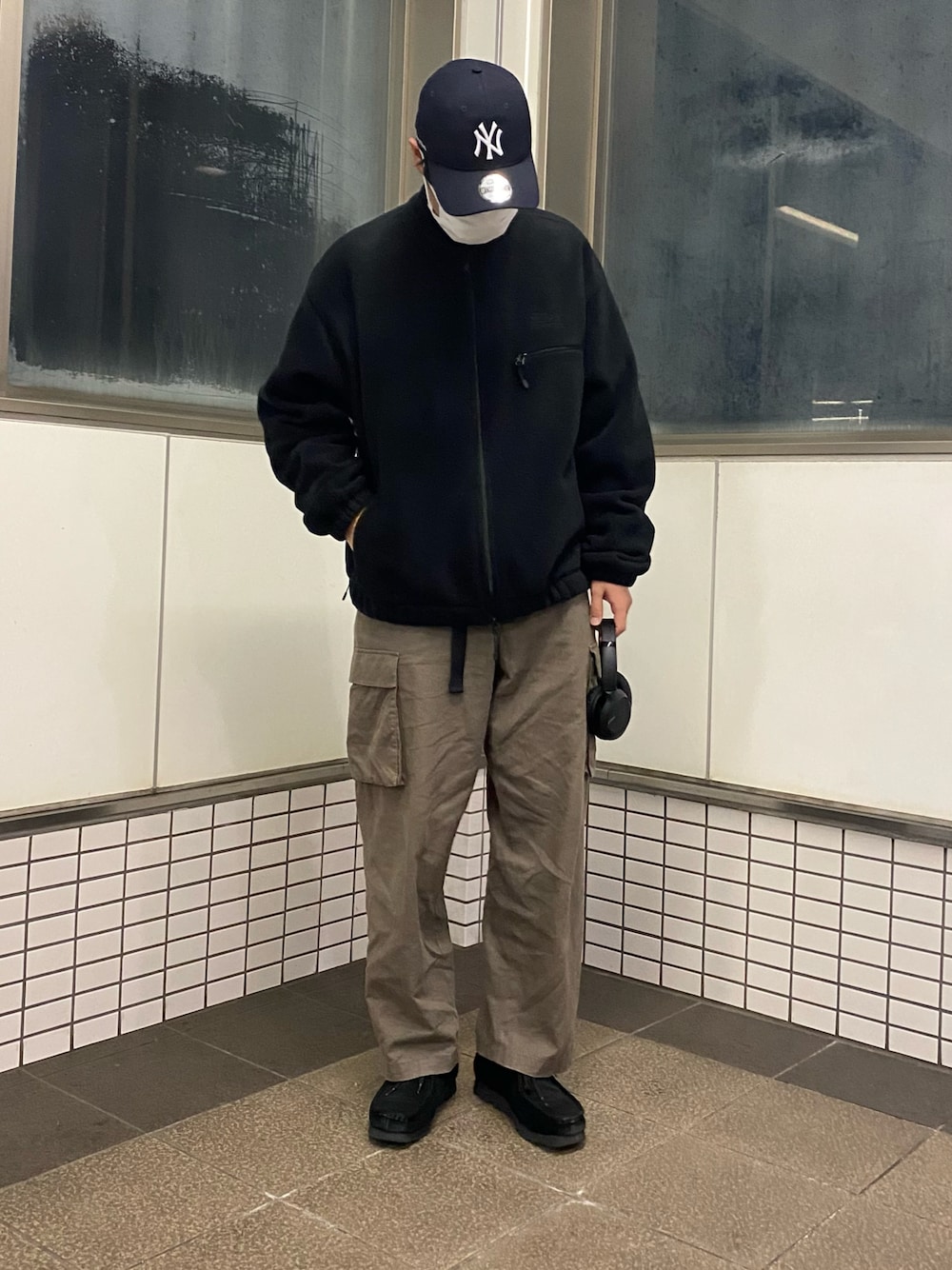 グリーン系のカーゴパンツ、ブラック系のブーツ、ブラック系のブルゾンを着用したメンズの春コーディネートの1枚目の写真