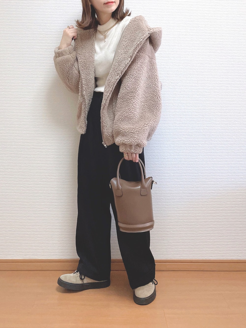ベージュ系のブルゾン、ホワイト系のニット/セーター、ブラック系のパンツを着用したレディースの冬コーディネートの1枚目の写真