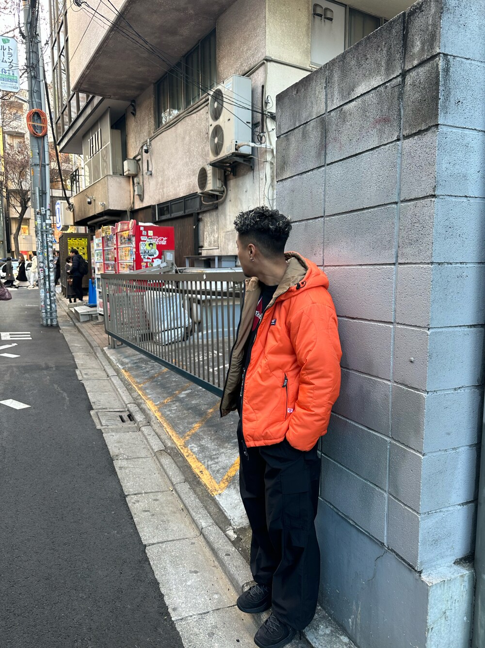 オレンジ系のマウンテンパーカー、ブラック系のカーゴパンツ、ブラック系のニット/セーターを着用したメンズの冬コーディネートの1枚目の写真