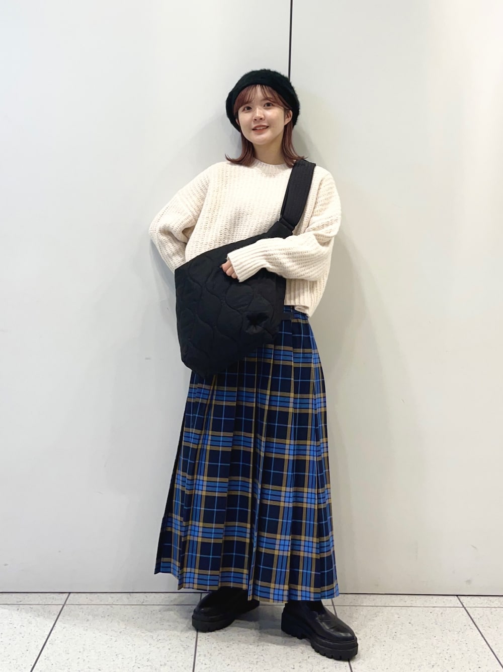 ブラック系のショルダーバッグ、ブルー系のスカート、ブラック系のブーツを着用したレディースの秋コーディネートの1枚目の写真