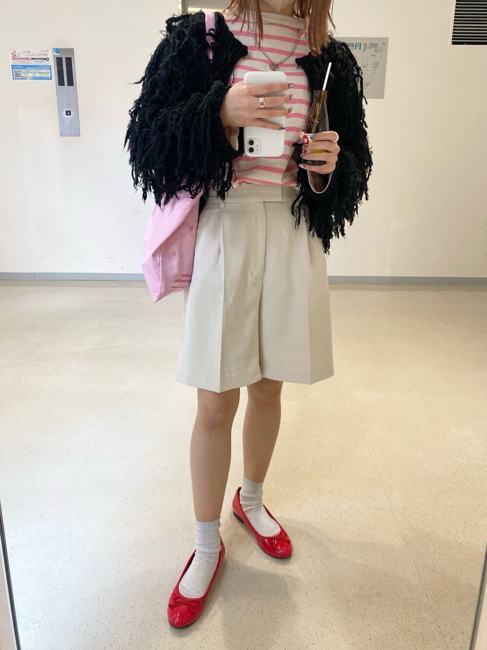 ホワイト系のパンツ、ピンク系のトートバッグ、ブラック系のカーディガン/ボレロを着用したレディースの冬コーディネートの1枚目の写真