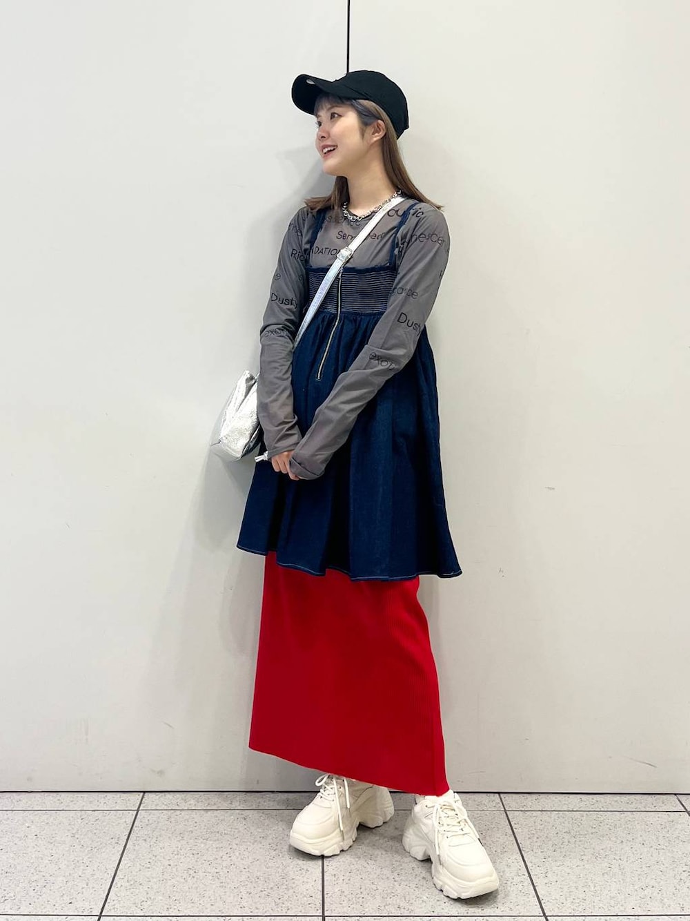 グレー系のTシャツ/カットソー、レッド系のスカート、ホワイト系のスニーカーを着用したレディースの春コーディネートの1枚目の写真