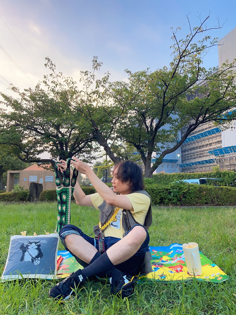 イエロー系のTシャツ/カットソー、ベージュ系のベスト、ブラック系のトートバッグを着用したメンズの秋コーディネートの1枚目の写真