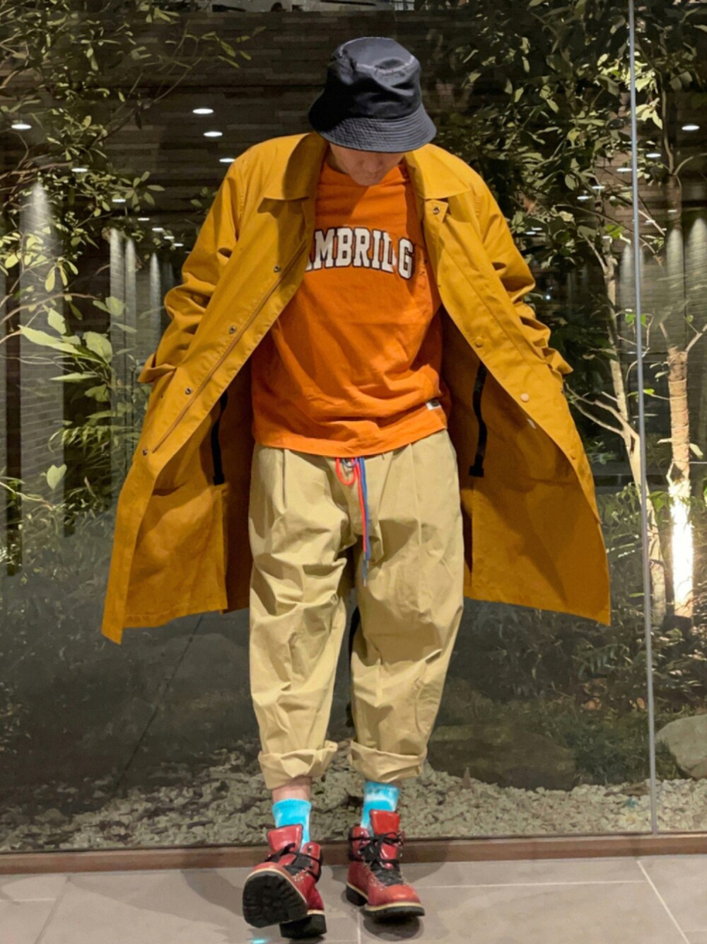 オレンジ系のTシャツ/カットソー、イエロー系のその他アウター、ベージュ系のチノパンツを着用したメンズの秋コーディネートの1枚目の写真