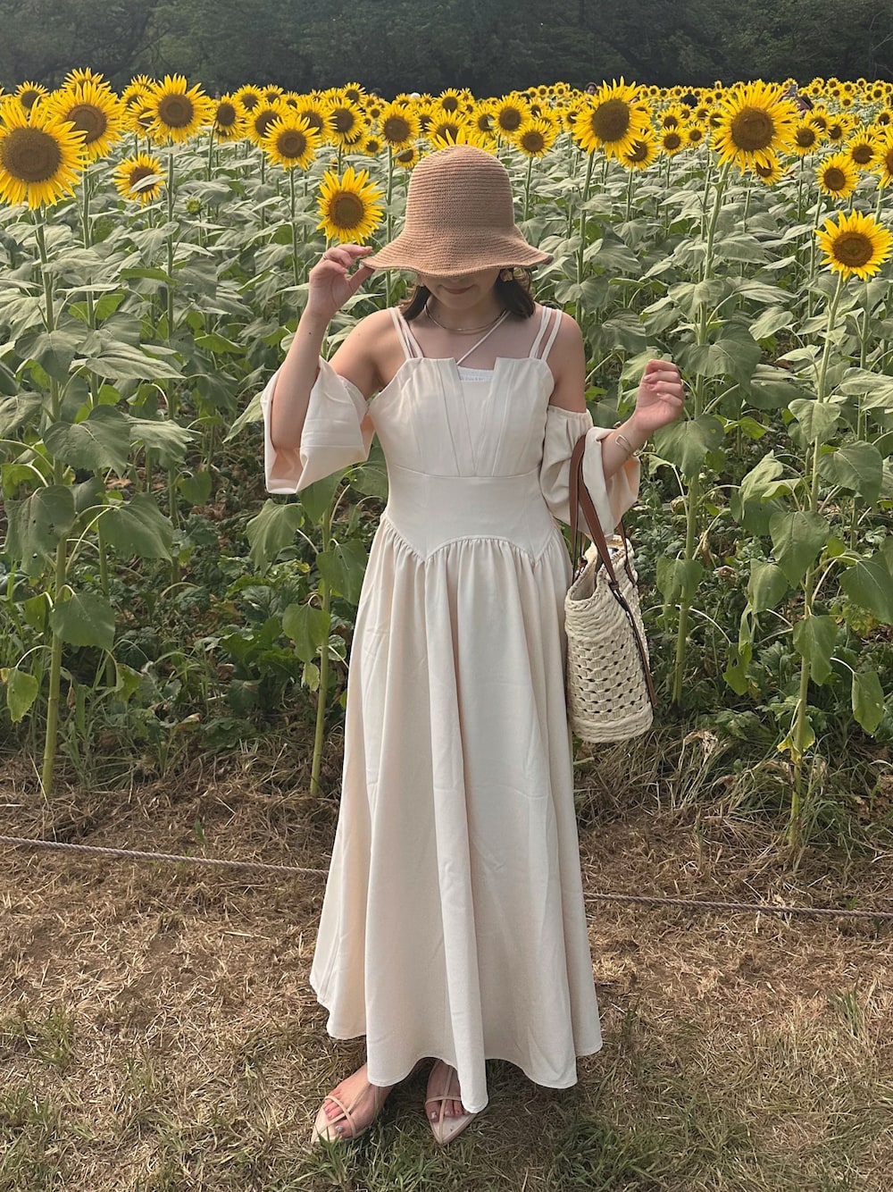 ホワイト系のワンピース、ホワイト系のかごバッグ、ベージュ系のサンダルを着用したレディースの夏コーディネートの1枚目の写真