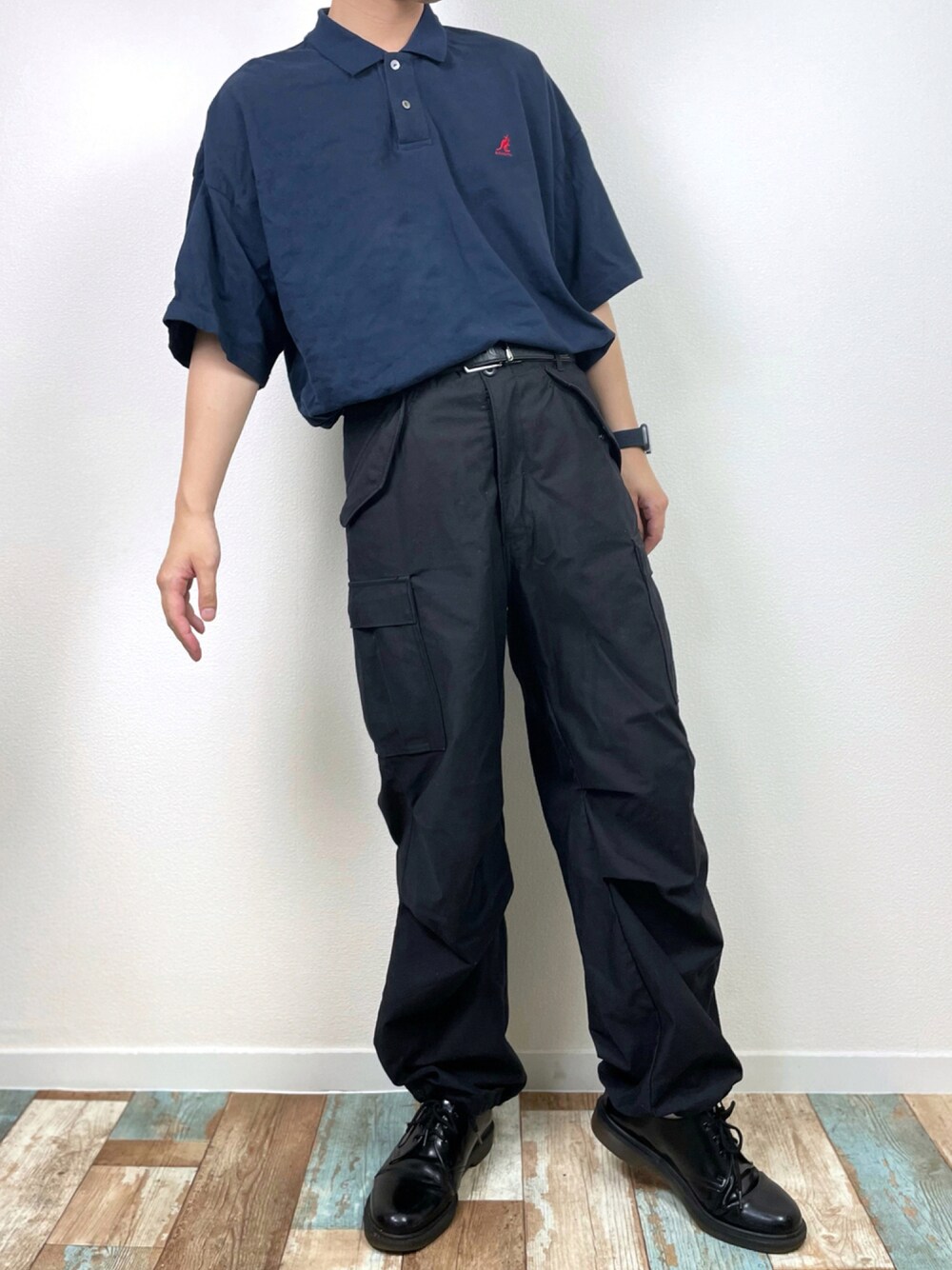 ブルー系のポロシャツ、ブラック系のカーゴパンツ、ブラック系のその他シューズを着用したメンズの夏コーディネートの1枚目の写真