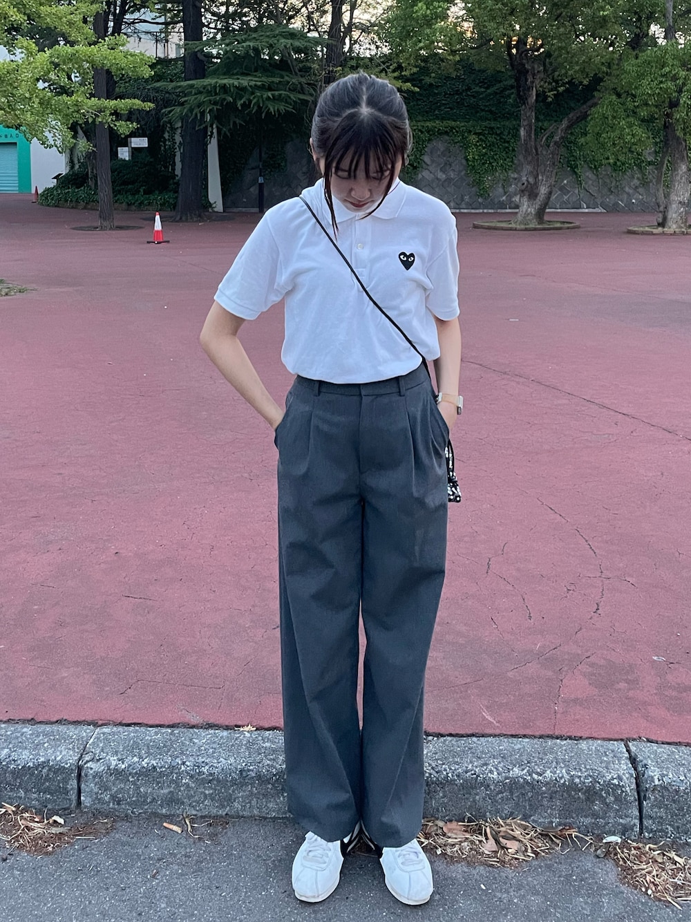 ホワイト系のスニーカー、シルバー系のショルダーバッグ、グレー系のスラックスを着用したレディースの夏コーディネートの1枚目の写真