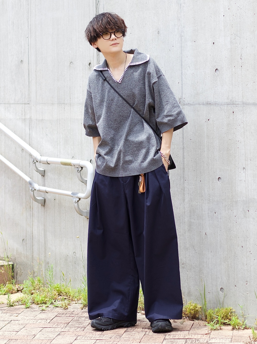 ブラック系のポロシャツ、ブルー系のスラックス、ブラック系のスニーカーを着用したメンズの夏コーディネートの1枚目の写真