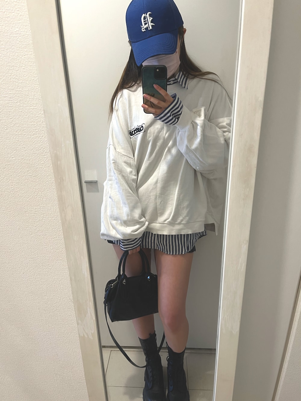 ブラック系のショルダーバッグ、ブラック系のブーツ、ブルー系のシャツ/ブラウスを着用したレディースの春コーディネートの1枚目の写真