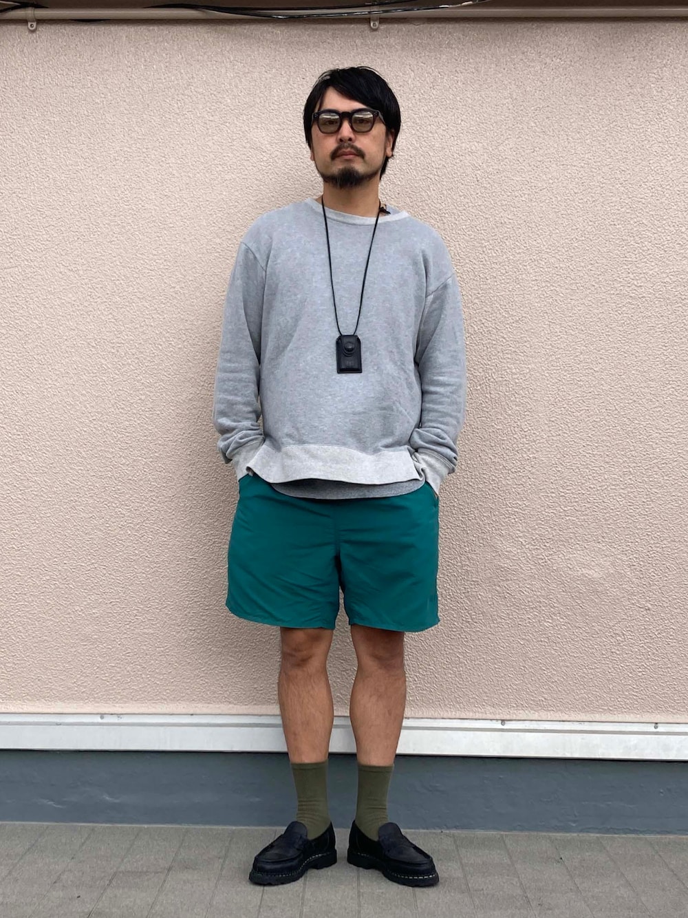 ブラック系のローファー、グリーン系のパンツ、ブラック系のネックレスを着用したメンズの春コーディネートの1枚目の写真