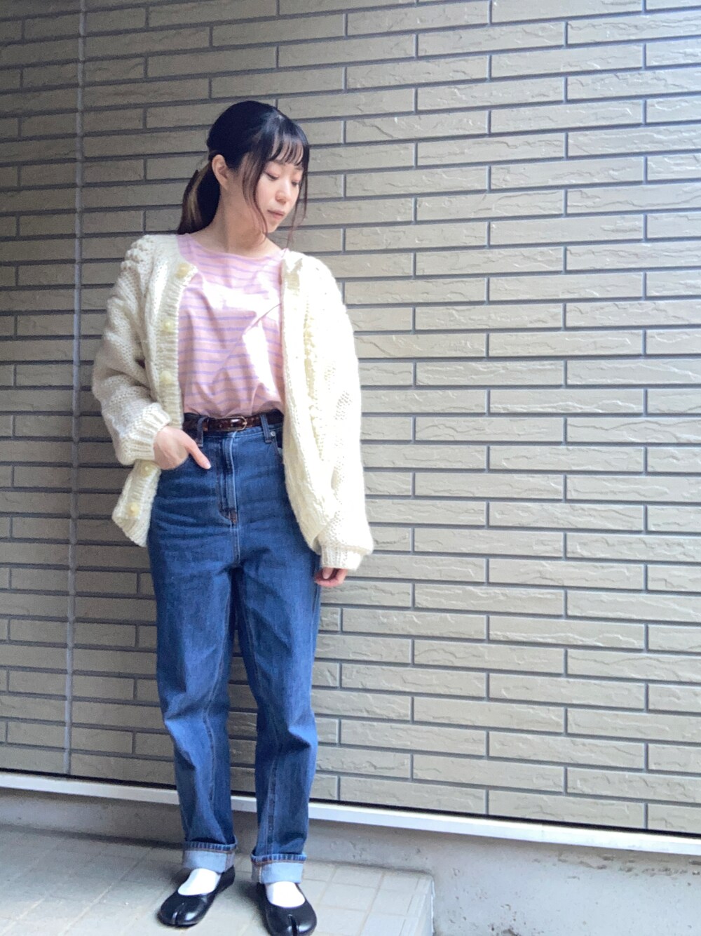 ホワイト系のカーディガン/ボレロ、ピンク系のTシャツ/カットソー、ブルー系のデニムパンツを着用したレディースの冬コーディネートの1枚目の写真