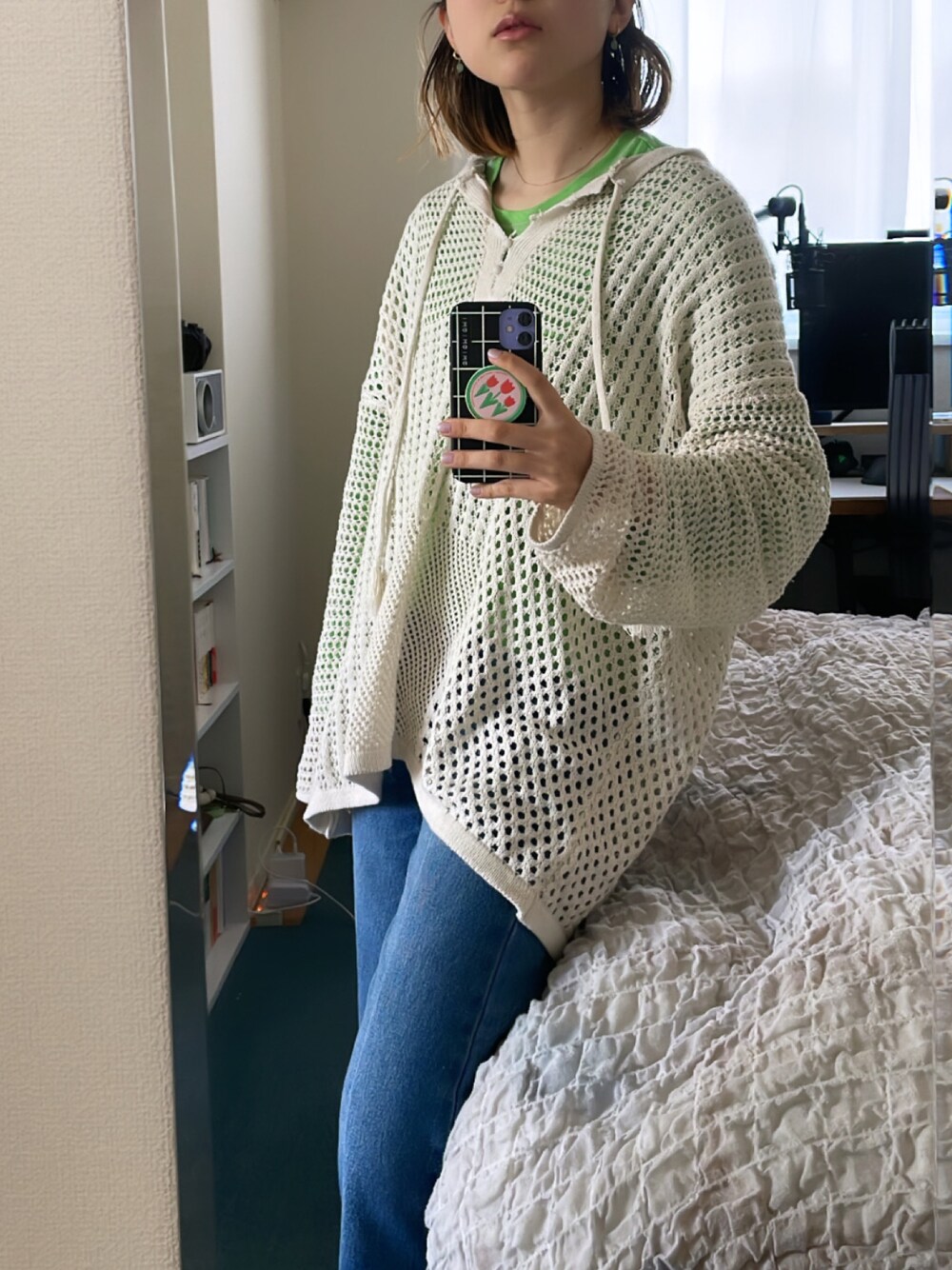 ブルー系のデニムパンツ、ベージュ系のニット/セーター、グリーン系のTシャツ/カットソーを着用したレディースの春コーディネートの1枚目の写真