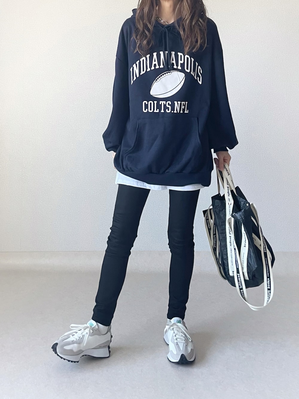 ブルー系のパーカー、ホワイト系のスカート、ブラック系のトートバッグを着用したレディースの秋コーディネートの1枚目の写真