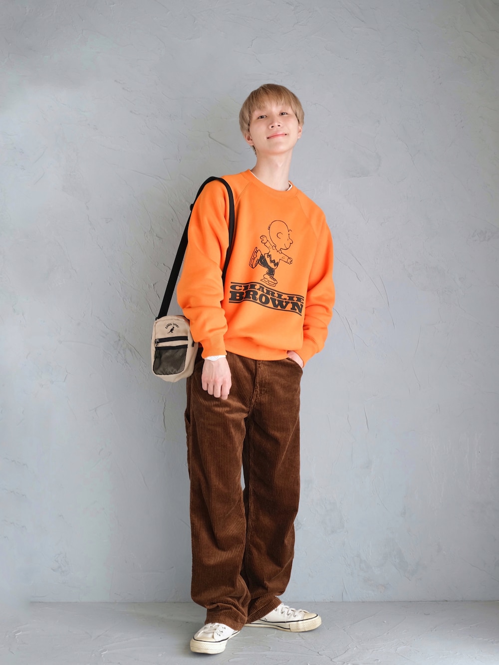 ホワイト系のスニーカー、ブラウン系のパンツ、オレンジ系のスウェットを着用したメンズの秋コーディネートの1枚目の写真