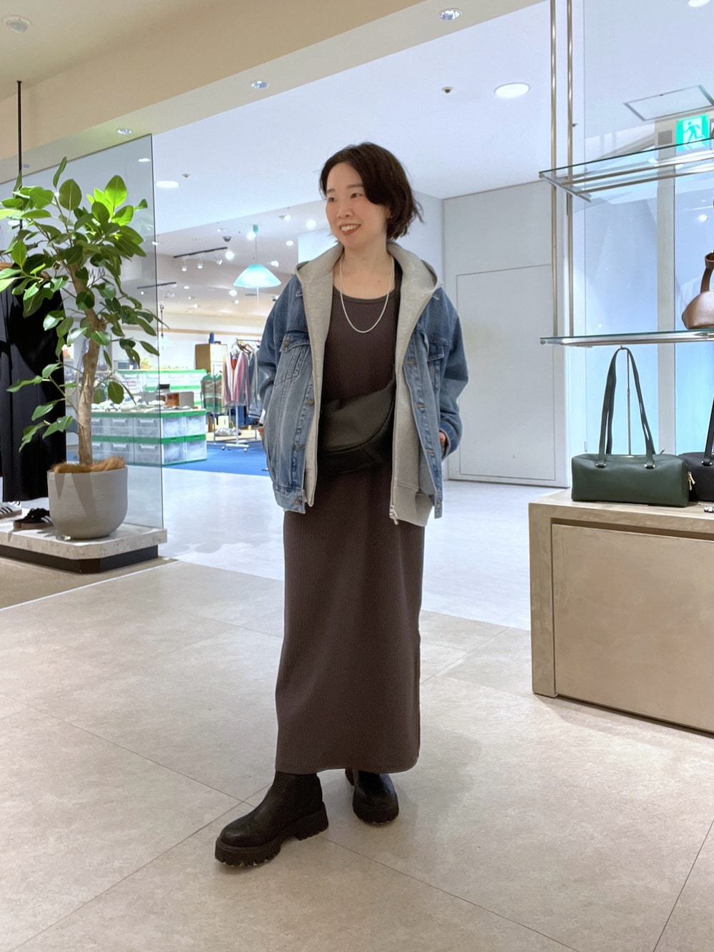 ブラウン系のワンピース、ブラック系のショルダーバッグ、ブラック系のブーツを着用したレディースの秋コーディネートの1枚目の写真