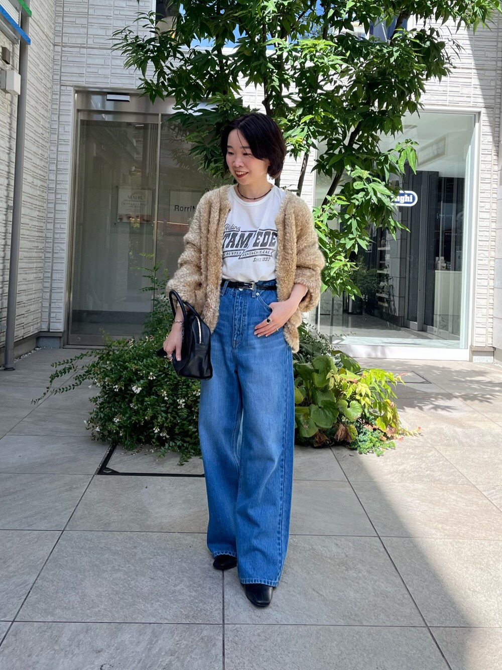ブルー系のデニムパンツ、ホワイト系のTシャツ/カットソー、ブラック系のボストンバッグを着用したレディースの秋コーディネートの1枚目の写真