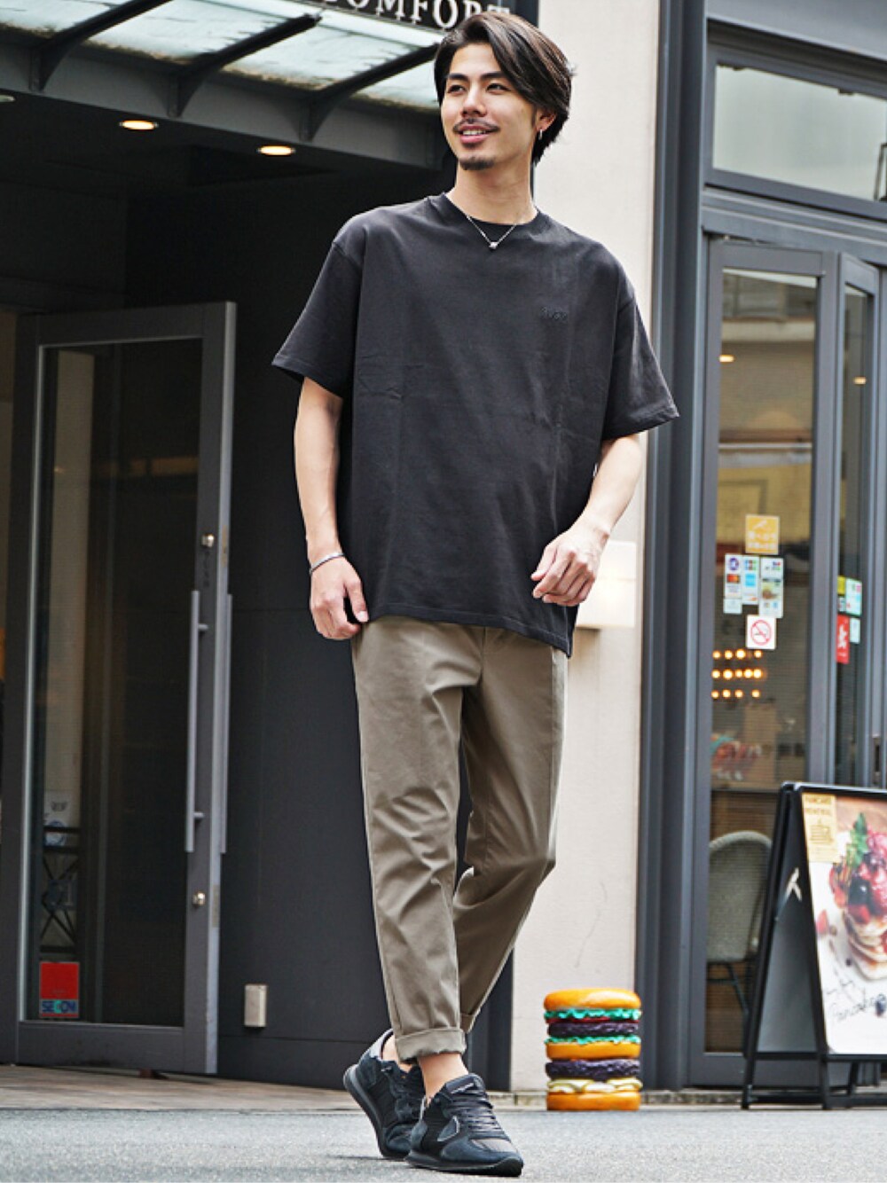 ベージュ系のチノパンツ、ブラック系のTシャツ/カットソーを着用したメンズの夏コーディネートの1枚目の写真