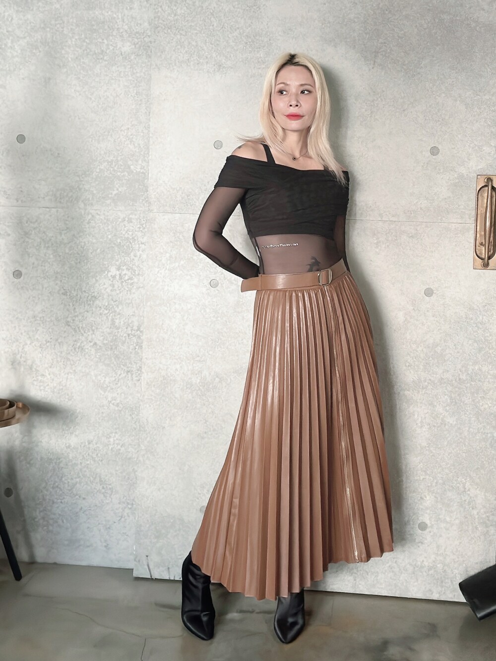 ブラウン系のスカート、ブラック系のブーティを着用したレディースの秋コーディネートの1枚目の写真