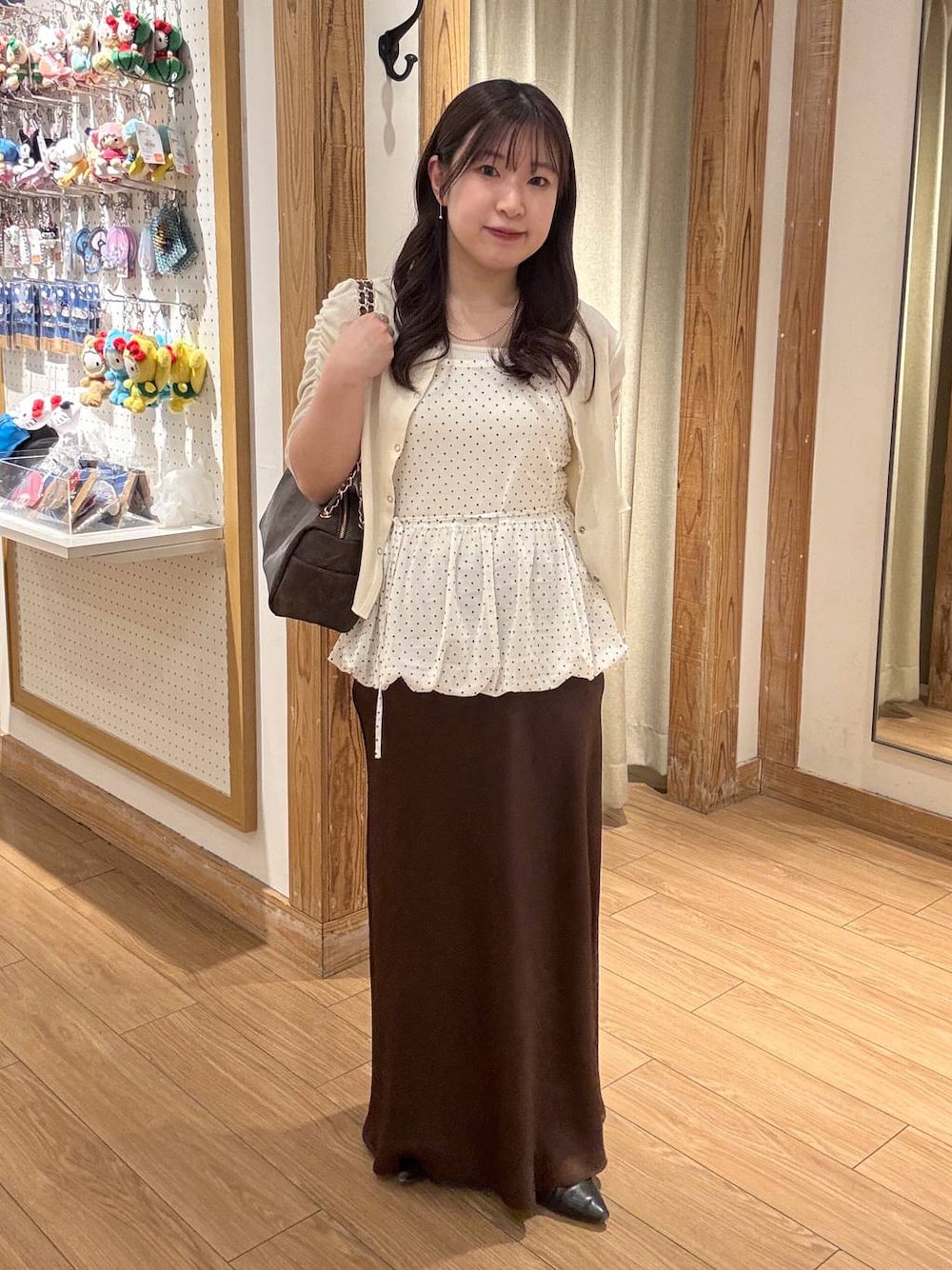 ブラウン系のスカート、ブラウン系のショルダーバッグ、ホワイト系のTシャツ/カットソーを着用したレディースの春コーディネートの1枚目の写真