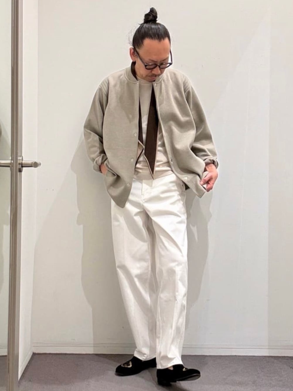 ブラック系のドレスシューズ、ホワイト系のデニムパンツ、ベージュ系のニット/セーターを着用したメンズの春コーディネートの1枚目の写真