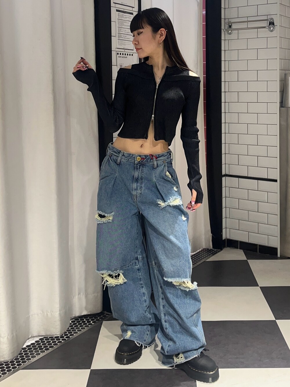 ブルー系のデニムパンツ、ブラック系のニット/セーター、ブラック系のブーツを着用したレディースの春コーディネートの1枚目の写真