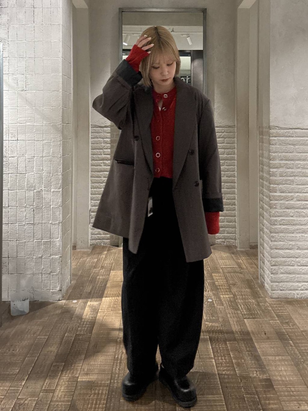 グレー系のテーラードジャケット、ブラック系のスラックス、レッド系のカーディガン/ボレロを着用したレディースの秋コーディネートの1枚目の写真