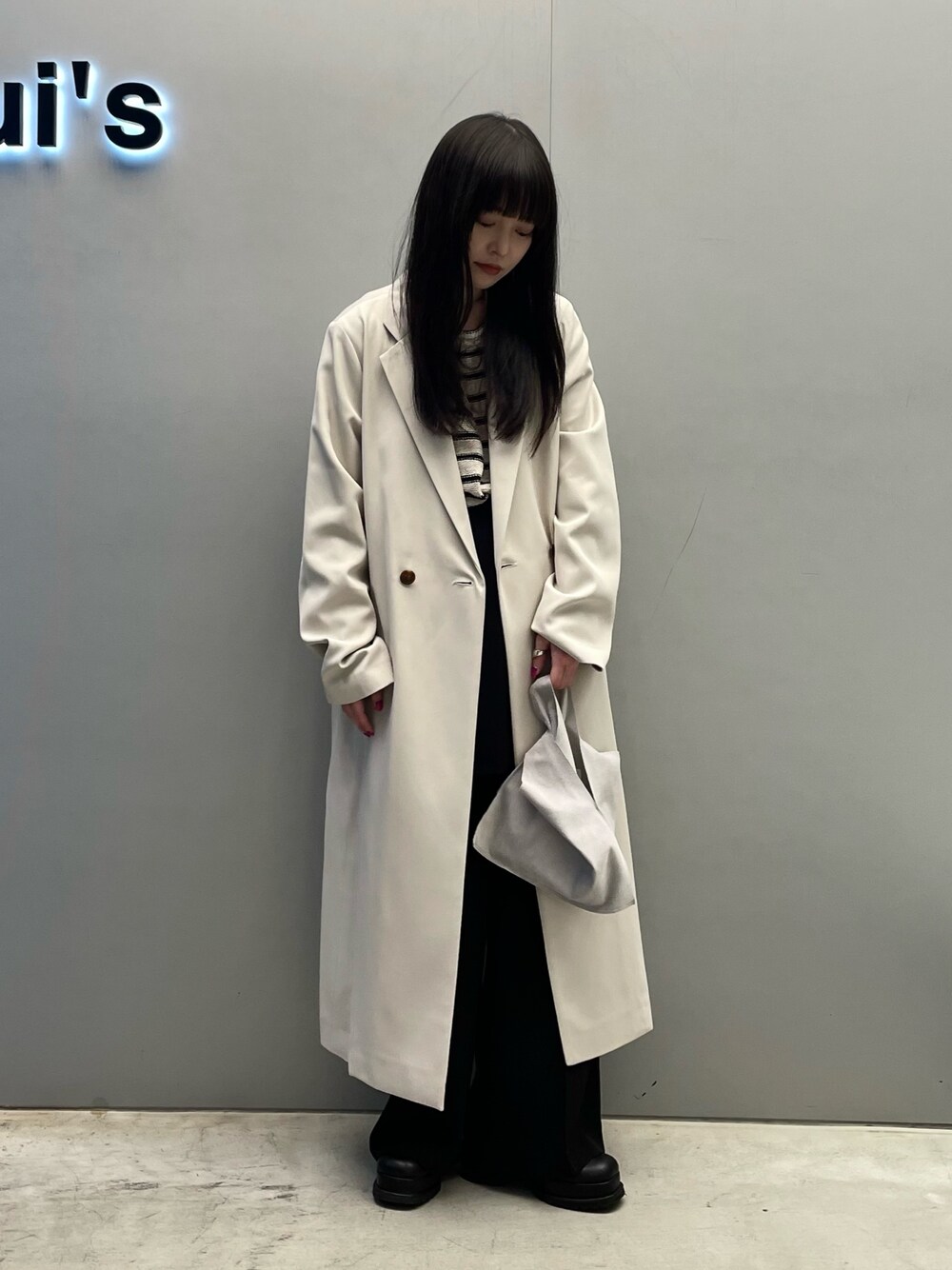 ベージュ系のチェスターコート、ホワイト系のトートバッグを着用したレディースの春コーディネートの2枚目の写真