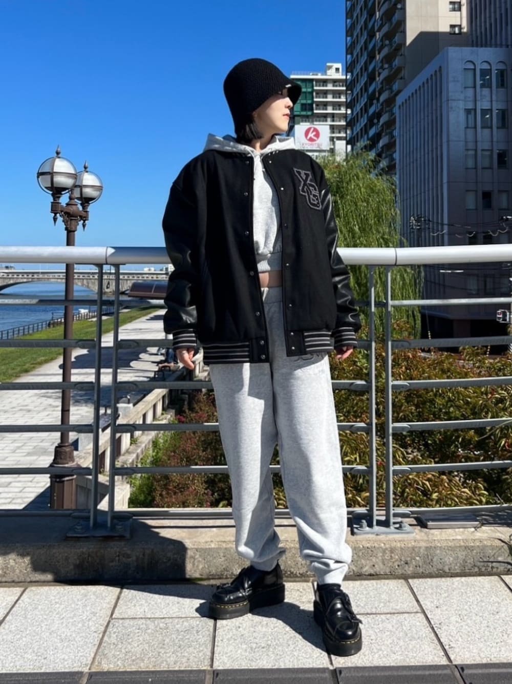 グレー系のスウェットパンツ、グレー系のパーカー、ブラック系のスタジャンを着用したレディースの秋コーディネートの1枚目の写真