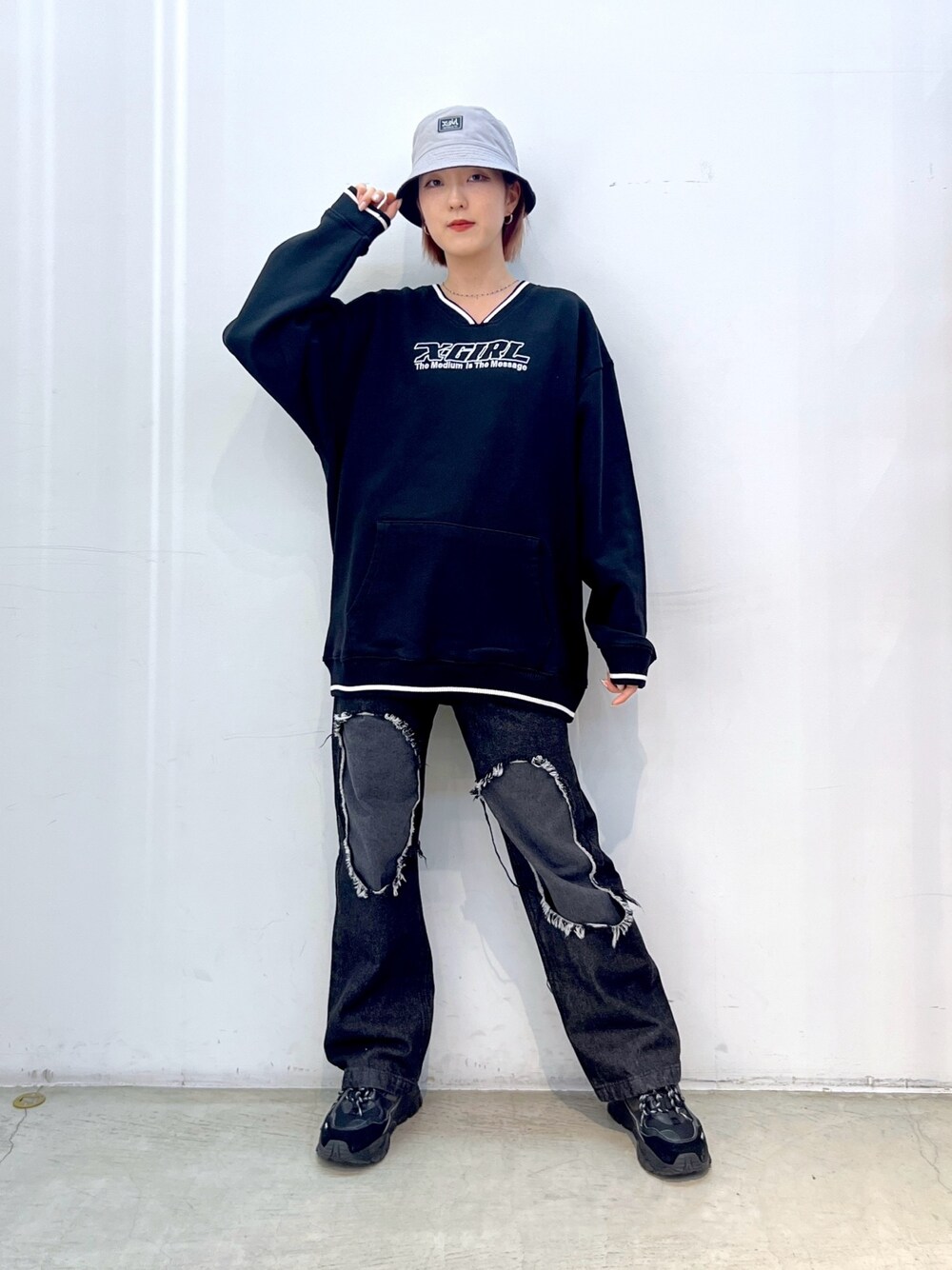 ブラック系のデニムパンツ、ブラック系のスウェット、ブルー系のハットを着用したレディースの冬コーディネートの1枚目の写真