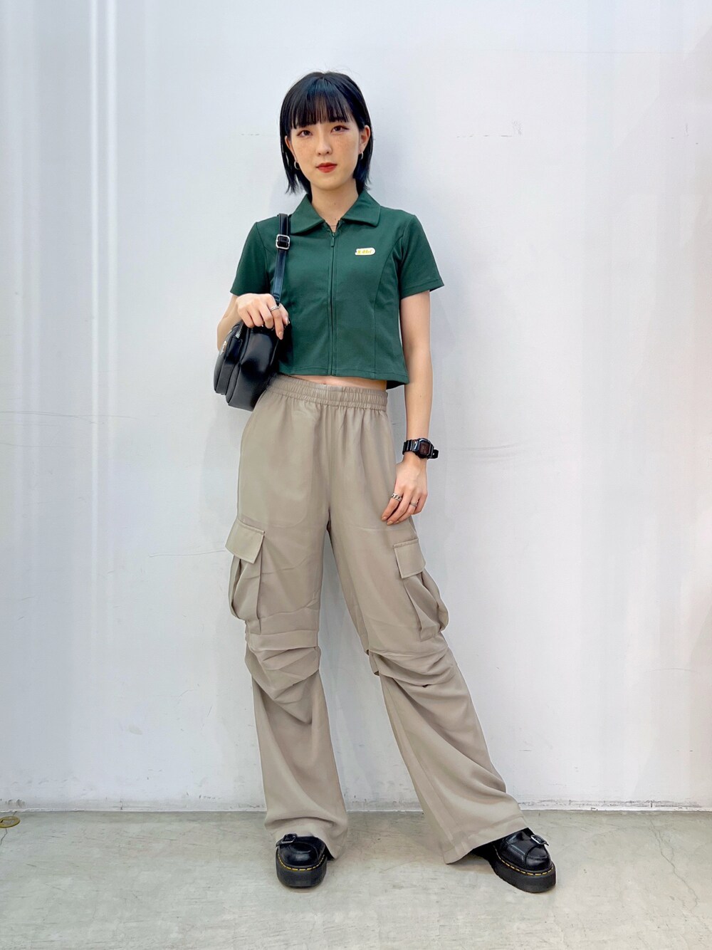 ベージュ系のその他パンツ、グリーン系のシャツ/ブラウス、ブラック系のショルダーバッグを着用したレディースの夏コーディネートの1枚目の写真