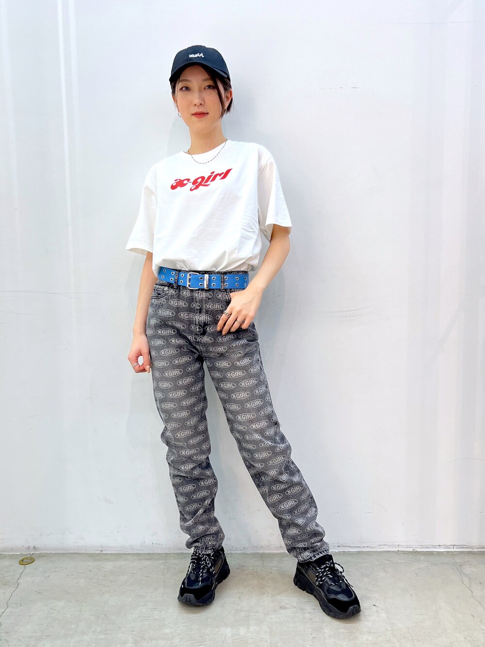 ブラック系のデニムパンツ、ホワイト系のTシャツ/カットソー、ブルー系のベルトを着用したレディースの春コーディネートの1枚目の写真