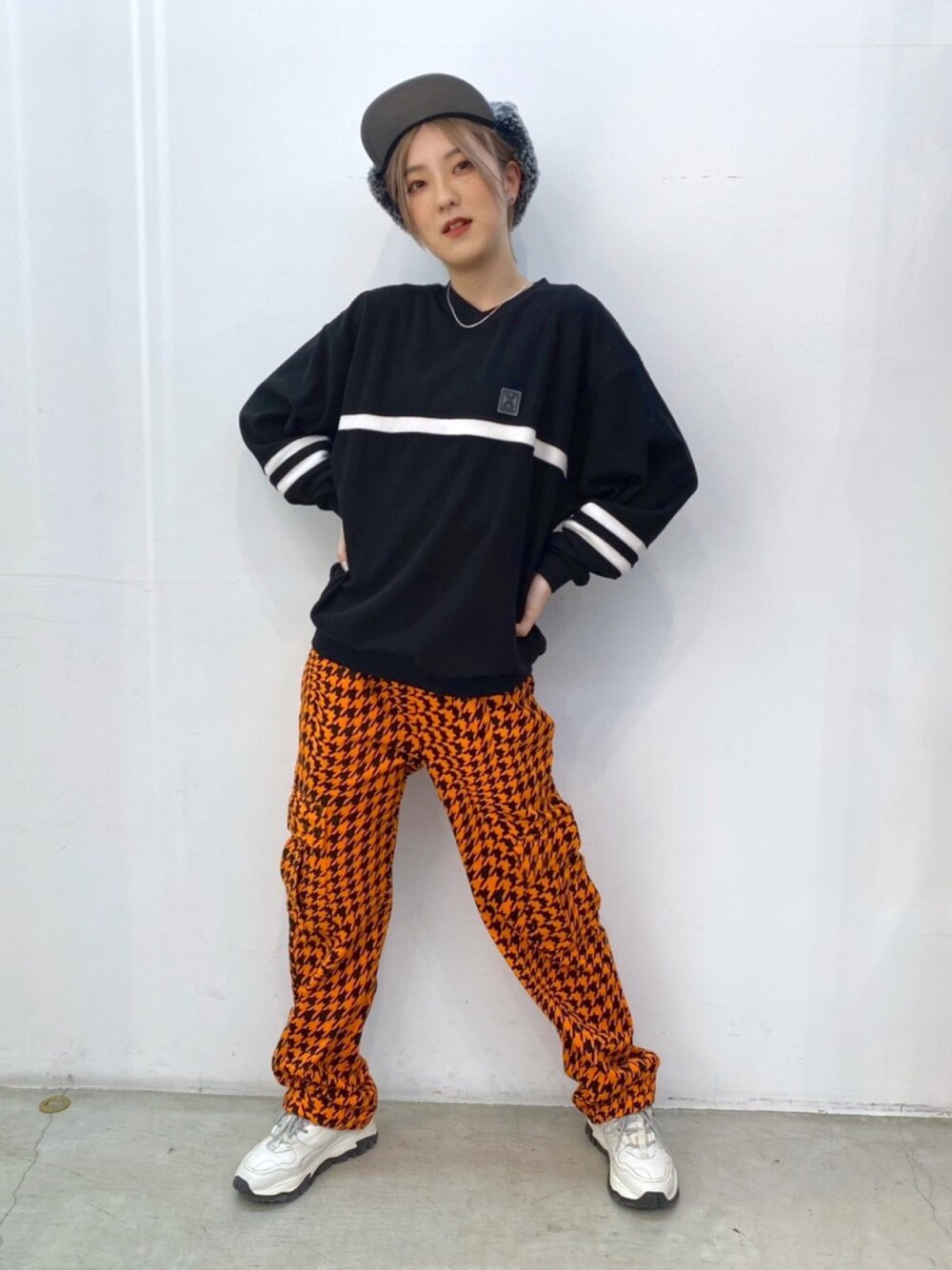 オレンジ系のその他パンツ、ブラック系のTシャツ/カットソー、グリーン系のキャップを着用したレディースの冬コーディネートの1枚目の写真