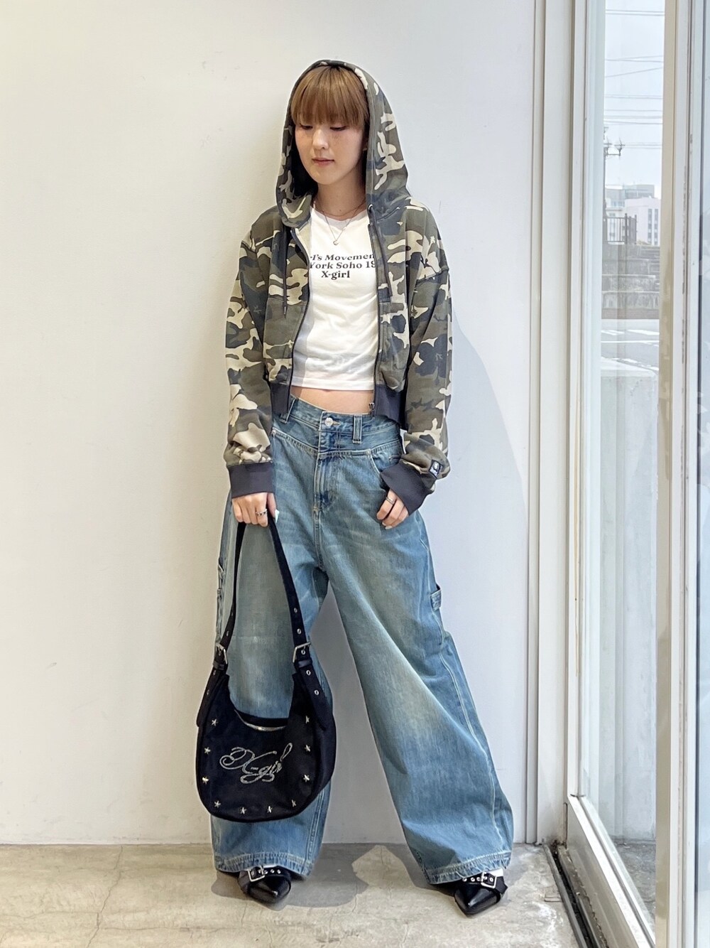 ブルー系のデニムパンツ、ブラック系のショルダーバッグ、ホワイト系のタンクトップを着用したレディースの春コーディネートの1枚目の写真