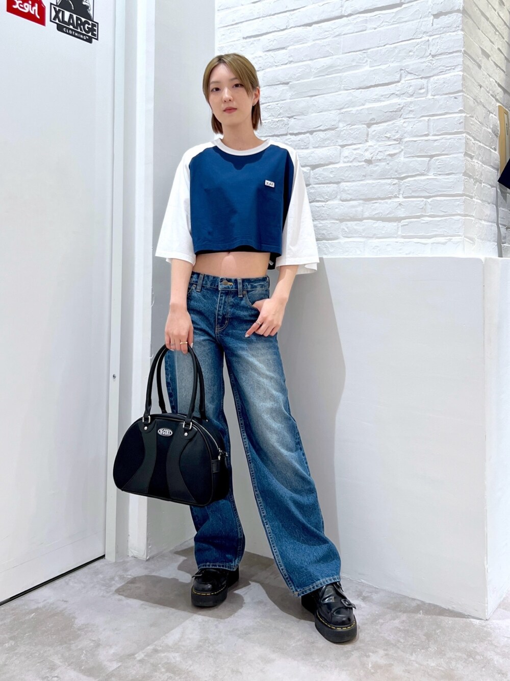 ブルー系のデニムパンツ、ブラック系のハンドバッグ、ブルー系のTシャツ/カットソーを着用したレディースの春コーディネートの1枚目の写真